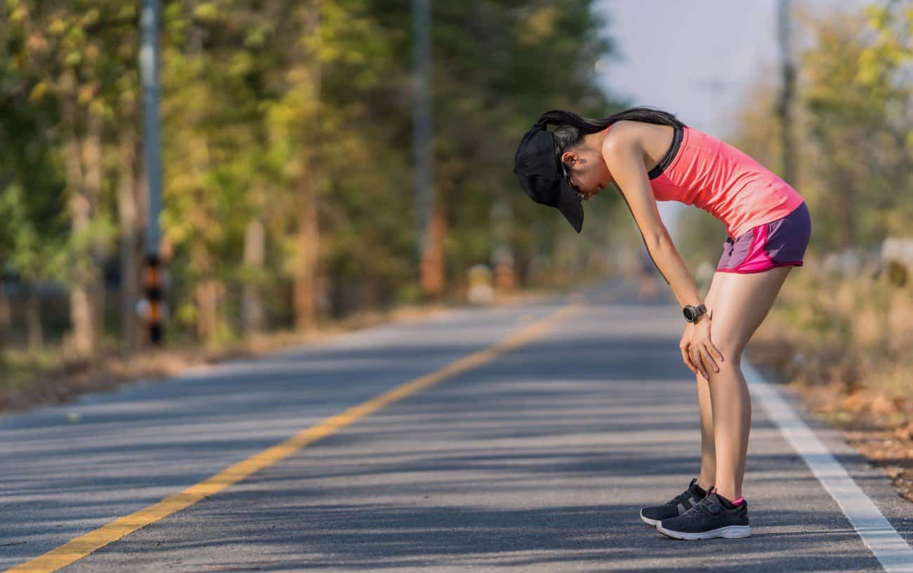 A woman hunched over on the side of the road, most likely after hitting the wall. 
