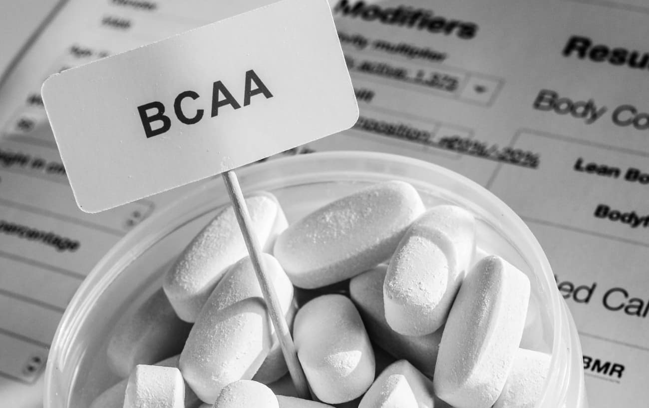 A container full of white pills and a BCAA sign. 