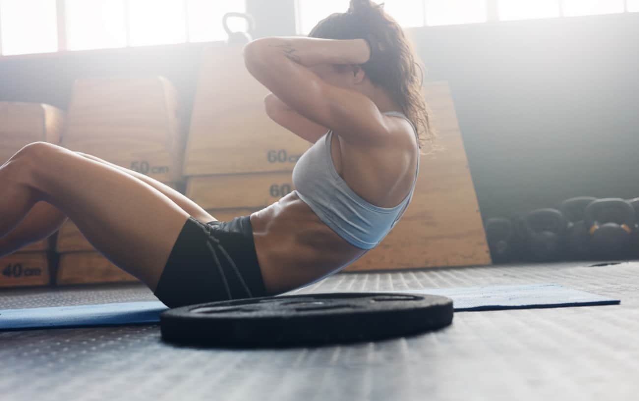A woman doing a sit-up in a gym. 