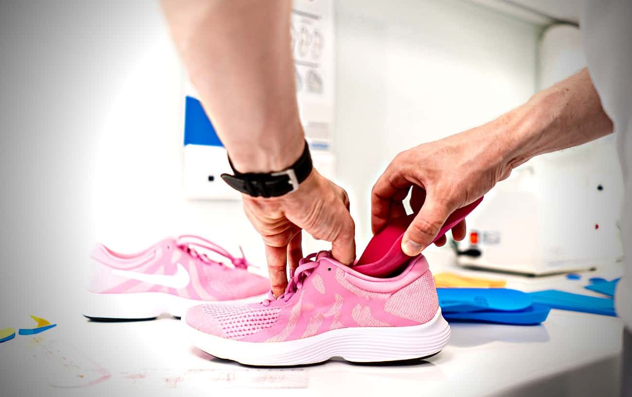 A person putting insoles into a running shoe.