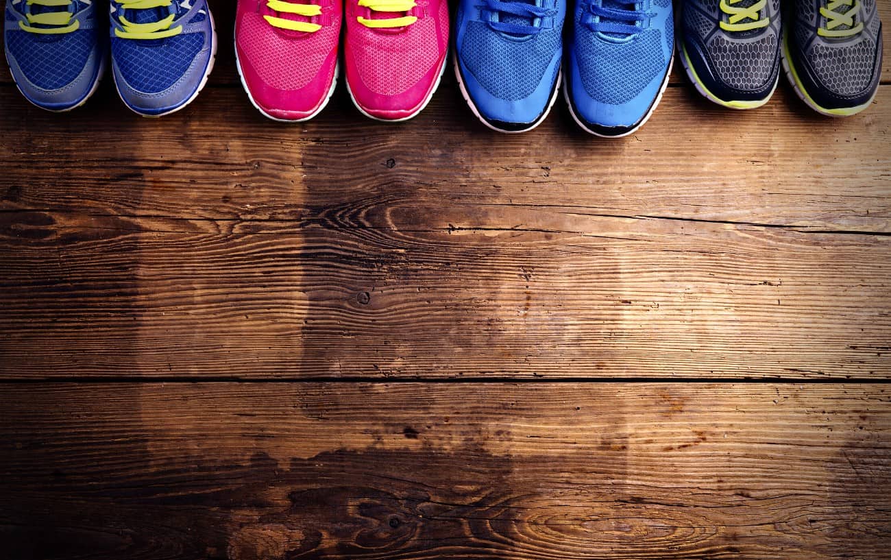A variety of running sneakers on a wood floor.