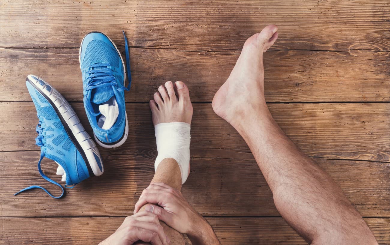 Bare feet next to blue running shoes on a wooden floor.