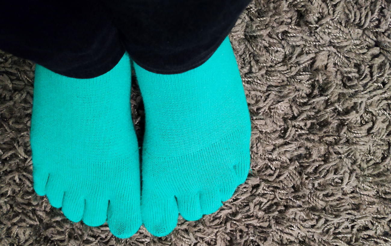 A pair of feet wearing toe socks.