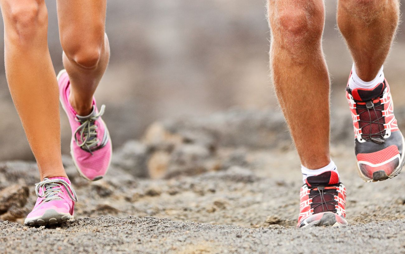 Two people running on gravel.