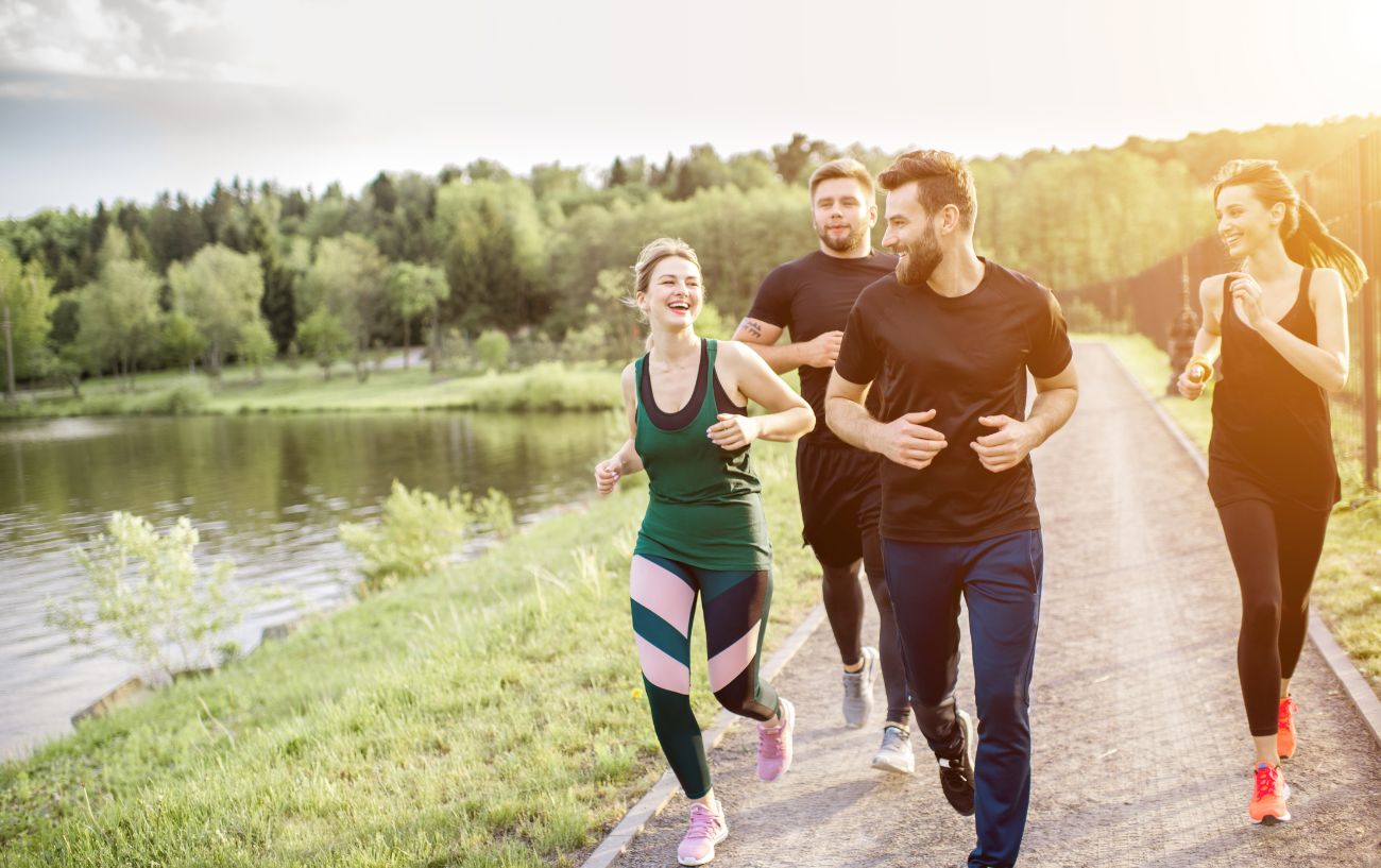 A group of runners run along a path while talking.