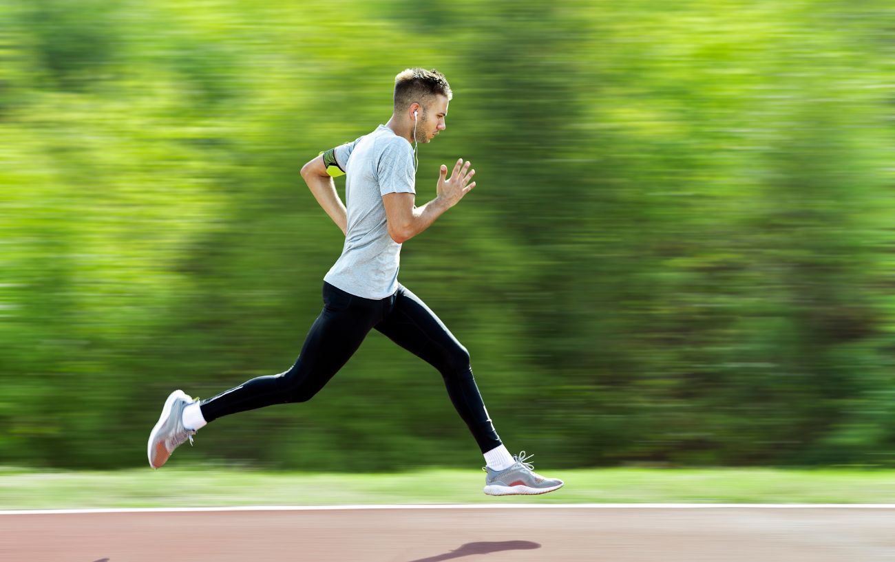 A runner sprints along a running treack with a blurred background.