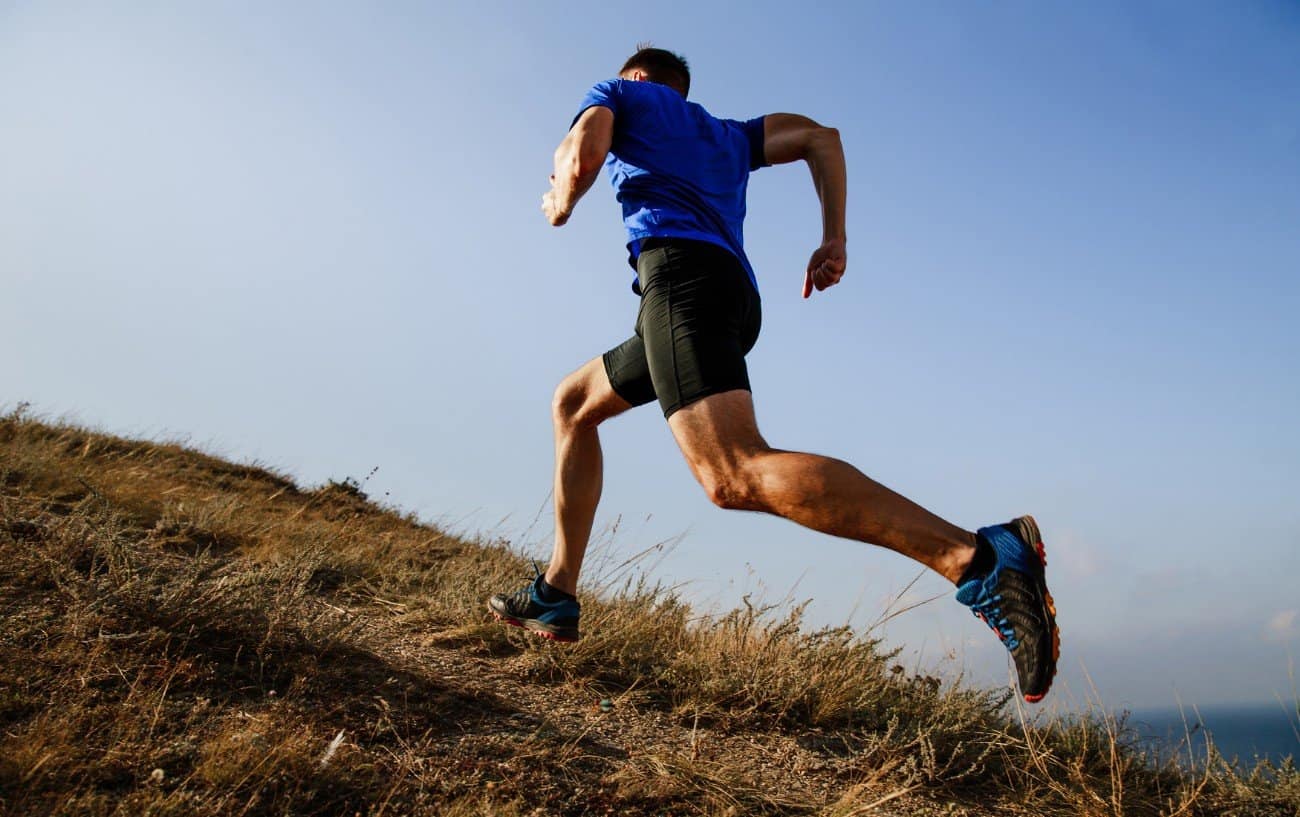 a man running up a grass trail