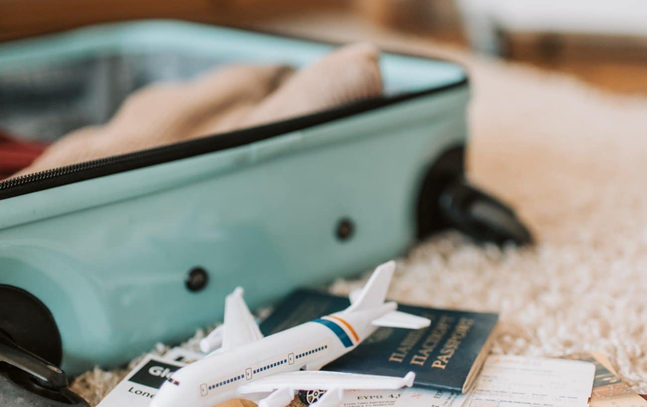 An open suitcase, toy airplane and passport on a rug. 