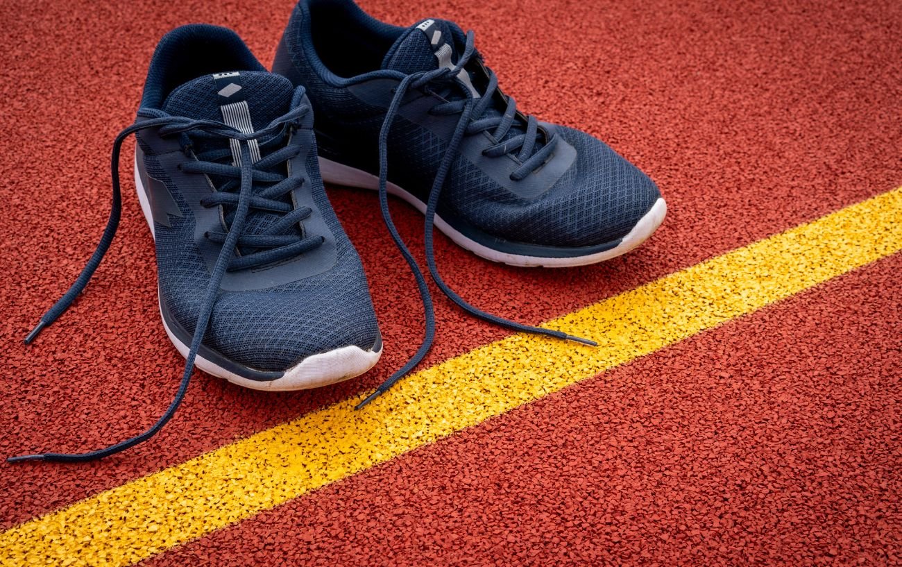 A pair of black running shoes on a track.
