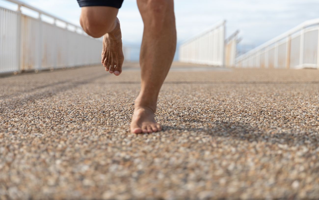 A person running barefoot on gravel.